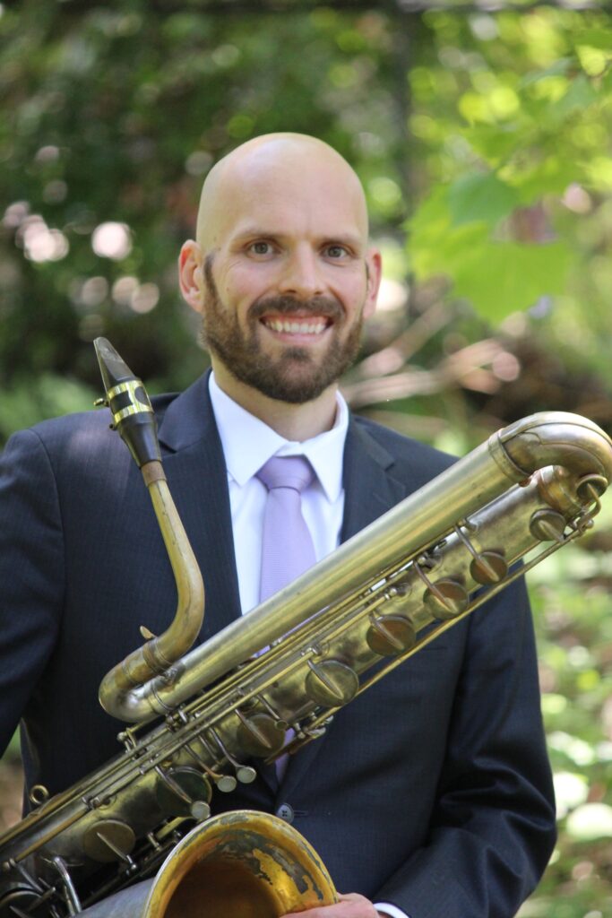 Headshot of Michael Hertel with his baritone saxophone.