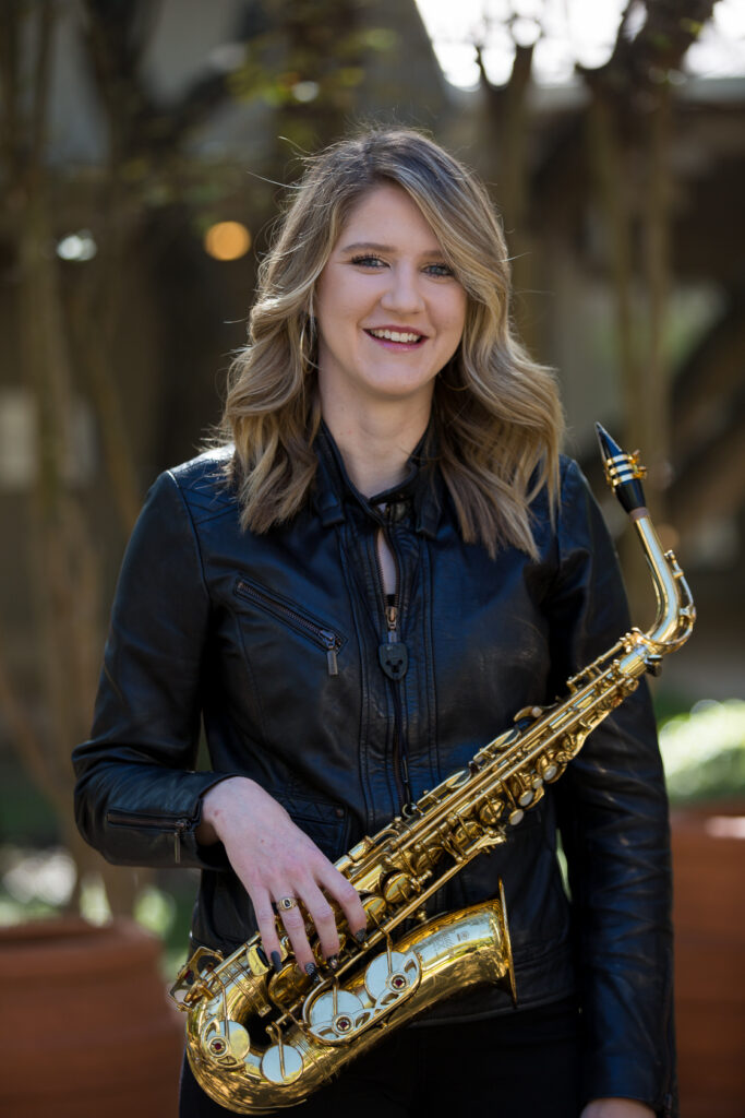 Headshot of Elyse Vest with her tenor saxophone.