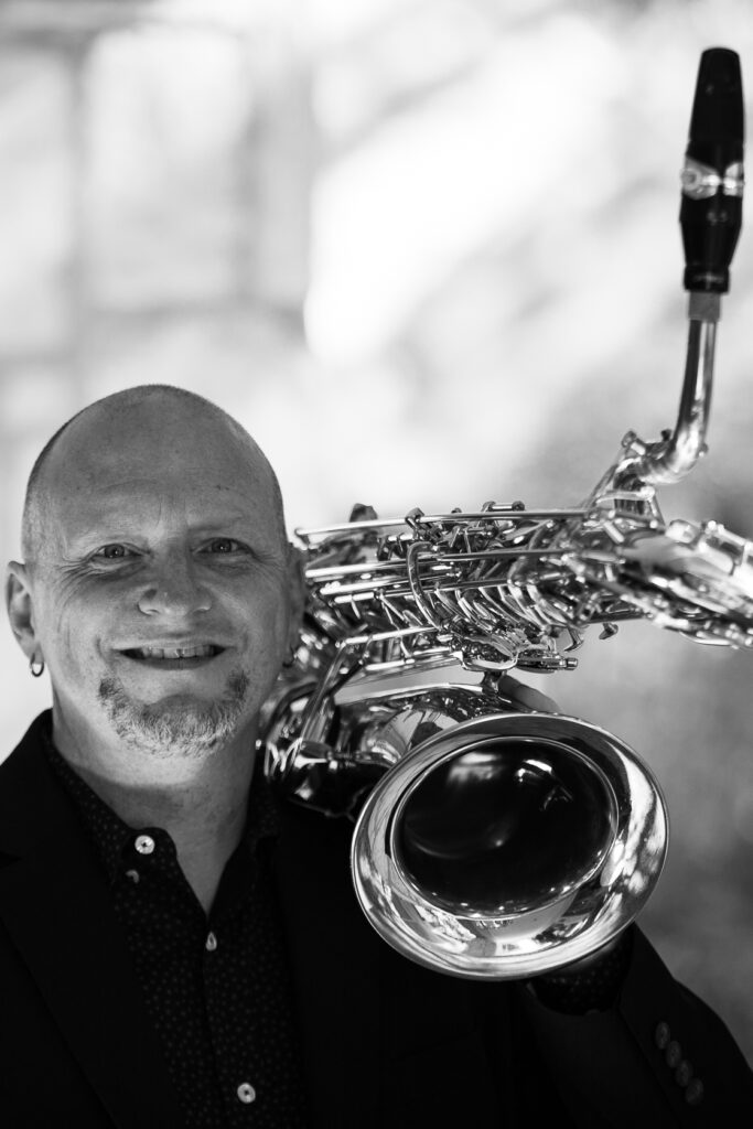 Headshot of Billy McPhail with his baritone saxophone.